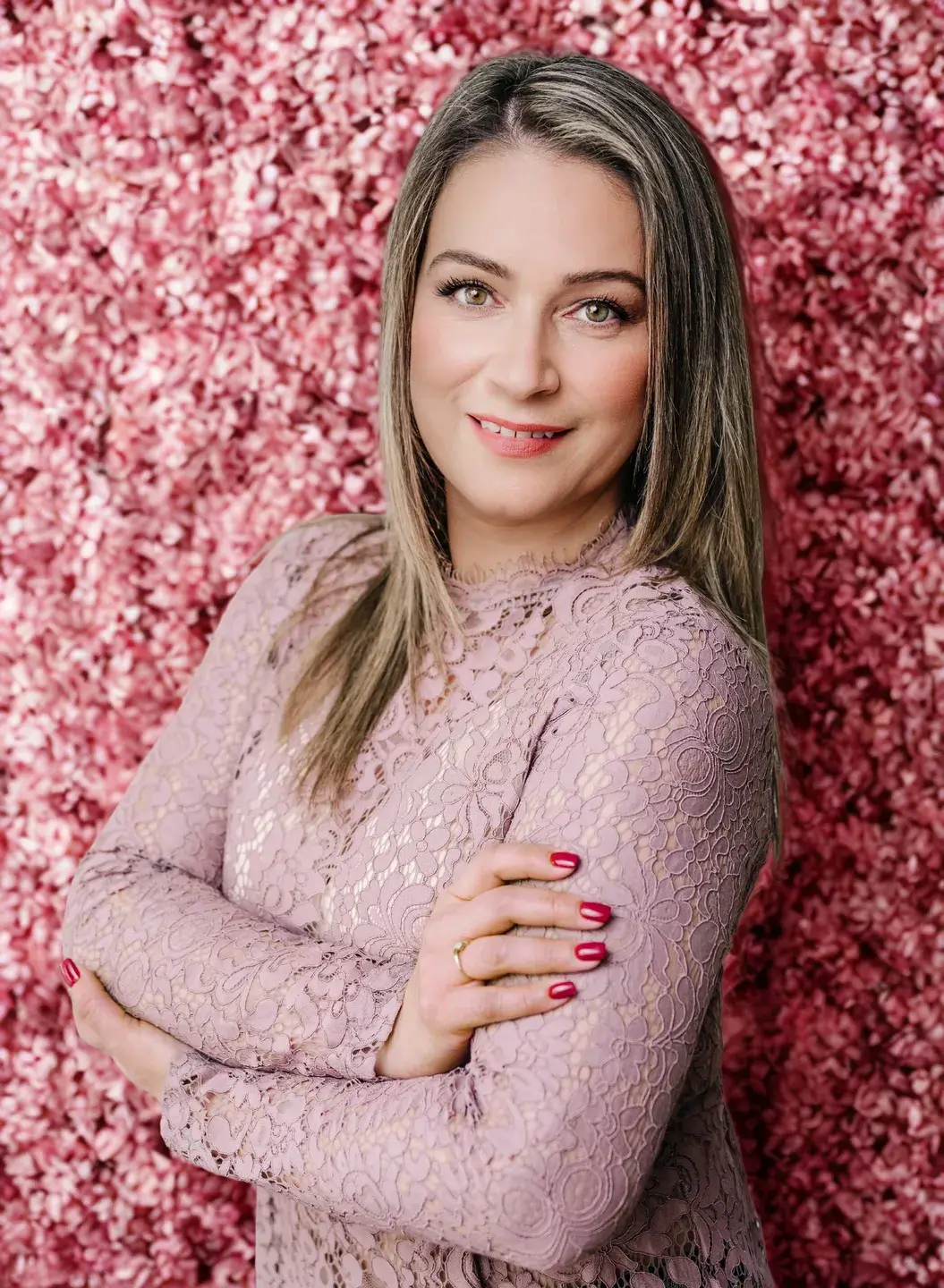 Woman in pink lace dress, floral background.