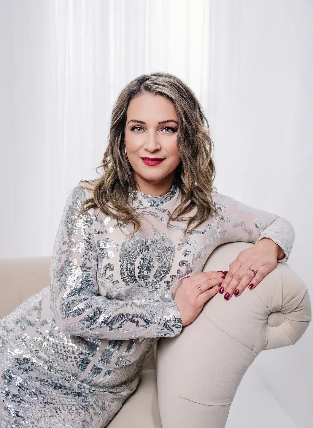 Woman in silver dress on white couch.
